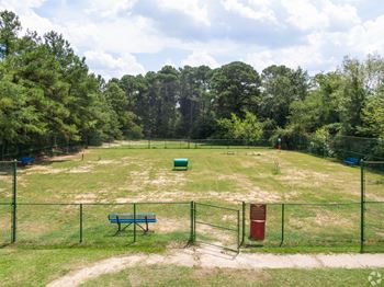 a park with a fenced in field and a park bench